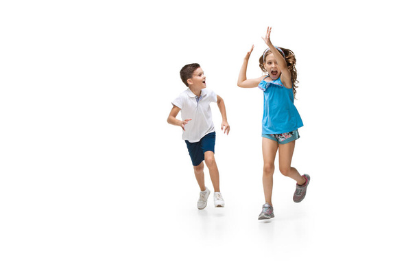 Happy little caucasian girl and boy jumping and running isolated on white background - Фото, изображение