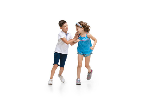 Happy little caucasian girl and boy jumping and running isolated on white background - Foto, Imagen
