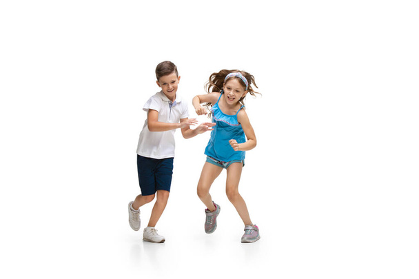 Happy little caucasian girl and boy jumping and running isolated on white background - Photo, image
