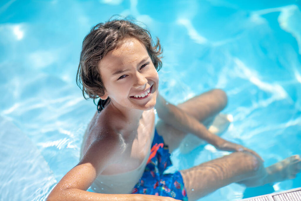 Boy sitting in the water in the pool - Photo, image