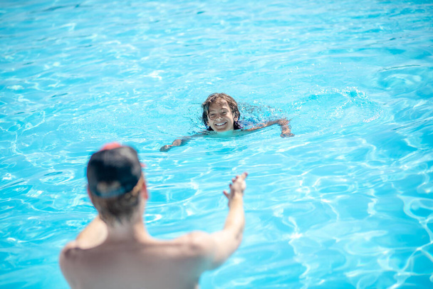 Man with back with outstretched arms to swimming boy - Фото, изображение
