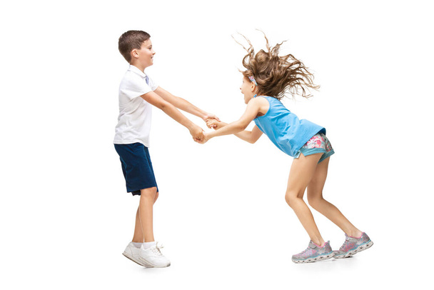 Happy little caucasian girl and boy jumping and running isolated on white background - Foto, afbeelding