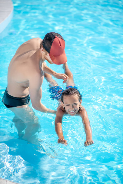 Instructor teaching a boy to keep afloat - Foto, afbeelding