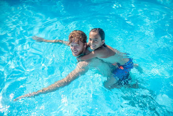 Tata z synem na plecach pływa w basenie - Zdjęcie, obraz
