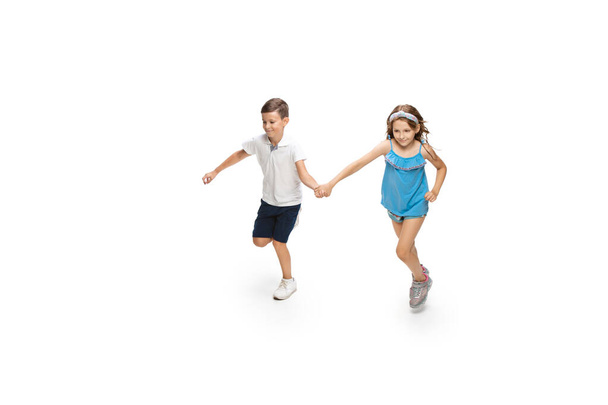 Happy little caucasian girl and boy jumping and running isolated on white background - Zdjęcie, obraz