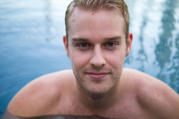 Portrét mladého pohledného muže s blond vlasy bez trička v bazénu - Fotografie, Obrázek