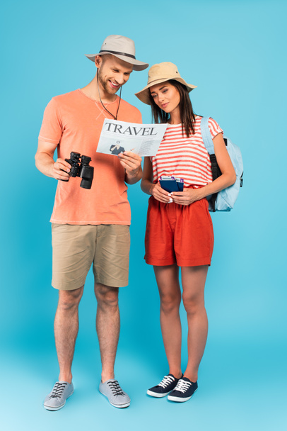 viajeros felices en sombreros leyendo el periódico de viaje en azul - Foto, Imagen