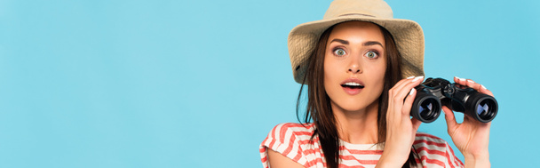 Şapkalı, şapkalı, elinde dürbün tutan mavi gözlü genç kadının panoramik görüntüsü. - Fotoğraf, Görsel