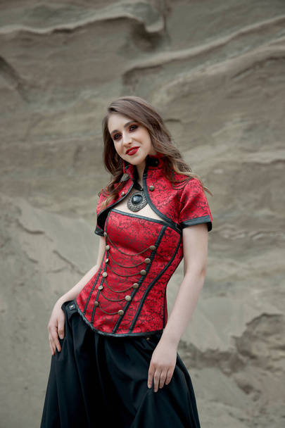 Beautiful anime woman in the sand. Red corset on the girl's body. Bright red makeup on the face - Fotoğraf, Görsel