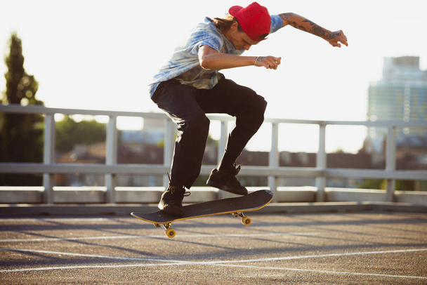 Skateboarder doing a trick at the citys street in summers sunshine - Фото, зображення