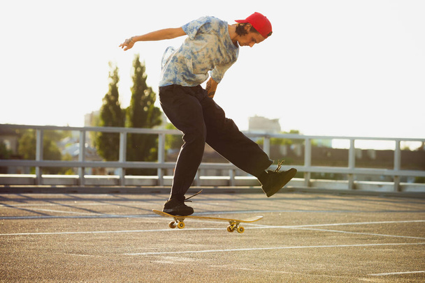 Skateboarder doing a trick at the citys street in summers sunshine - Photo, image
