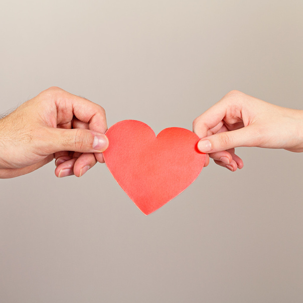 Man and woman hands holding red paper heart - Fotó, kép