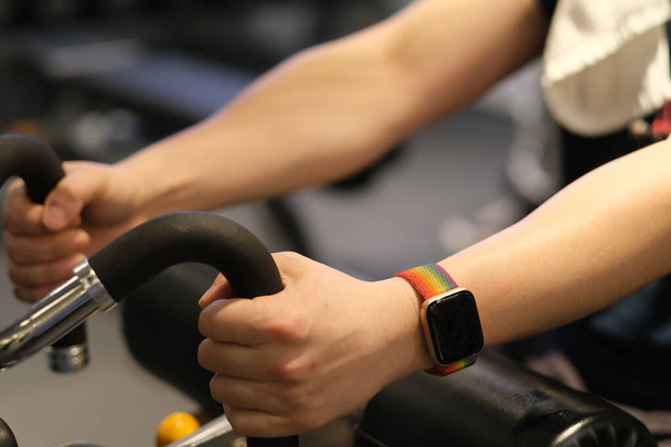 close up man's arm wearing smart watch, exercising on gym equipment. blur background - Photo, Image