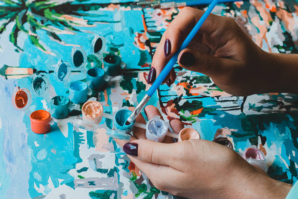 Sanatçı kadının elleri, salgın sırasında fırça ve boya tutarken hobi olarak resim yapıyor.  - Fotoğraf, Görsel