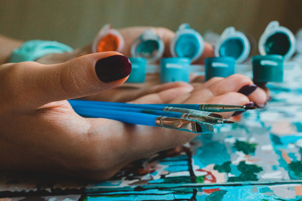 manos de la artista mujer está sosteniendo pinceles y pintura en el tiempo libre durante el brote pandémico pintura como un hobby
  - Foto, imagen