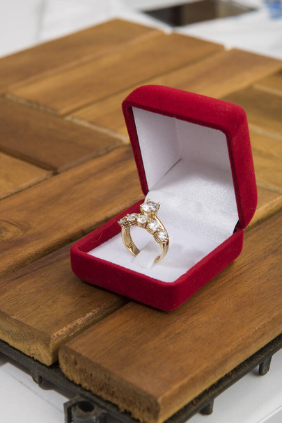Női ezüst gyűrűk piros bársonydobozban, fapadlón. - Fotó, kép