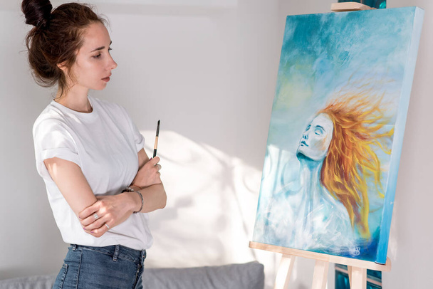 beautiful woman holding paintbrush, happy looking enjoying picture, inspired drawing picture, girls with orange hair. Home workshop. Emotions fantasy, enjoyment creativity inspiration. Art painting. - Photo, Image