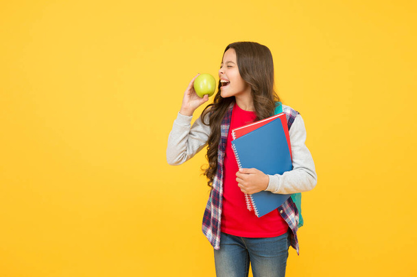 Clever eating. Little kid eat apple yellow background. School break. Fruit snack. Brain food. Cognitive health. Diet and dieting. Every girl should be eating healthy food, copy space - Fotó, kép