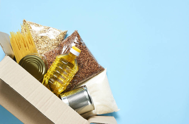 Food delivery. Essential products: buckwheat, spaghetti, sunflower oil, canned food. Food box. - Foto, Imagen