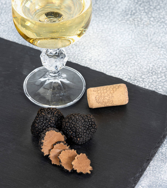 Black truffles and slices with white wine on black stone background. High quality photo - Photo, Image