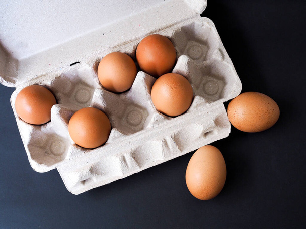 Acima de painéis de ovos de papel reciclado com ovos isolados em fundo escuro. Embalagem ecológica
. - Foto, Imagem