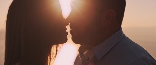 Close up de um jovem casal beijando ao pôr-do-sol, com belo brilho solar atrás deles. Movimento lento
.   - Filmagem, Vídeo