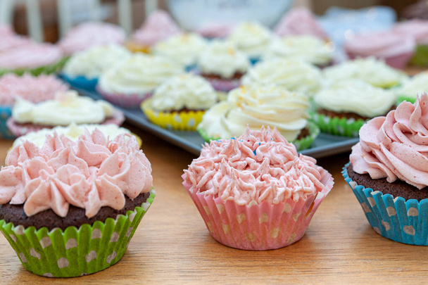 Home ψημένα cupcakes όμορφα διακοσμημένα με βουτυρόκρεμα στην κορυφή τοποθετούνται σε ξύλινο τραπέζι. - Φωτογραφία, εικόνα