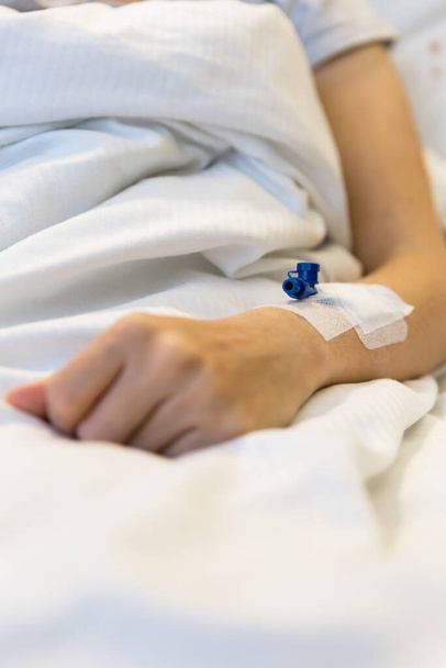 mujer con catéter venoso en el brazo, se encuentra en una cama de hospital - Foto, imagen