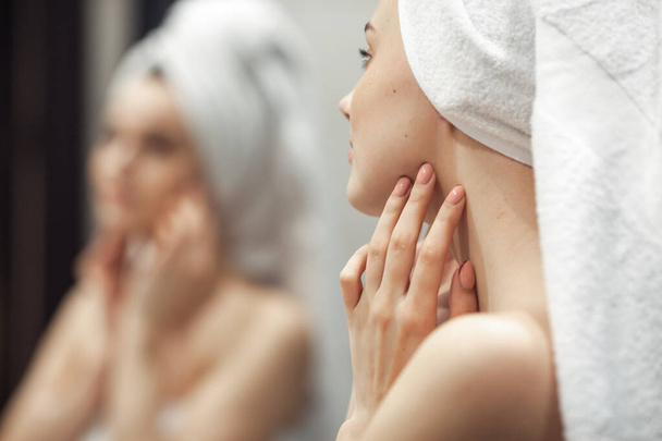 Young woman in bathroom behind mirror. Skincare  treatment concept - Fotó, kép