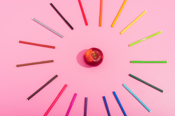κορυφαία άποψη του νόστιμου ώριμου μήλου σε πλαίσιο από χρωματιστά στυλό τσόχινα σε ροζ - Φωτογραφία, εικόνα