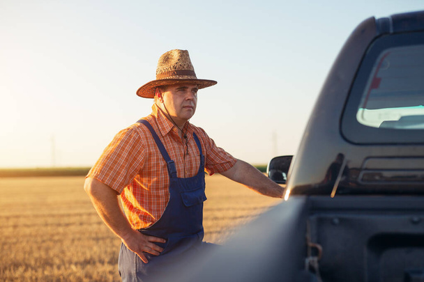 Trendy farmer standing proudly in front of his truck. - Fotó, kép