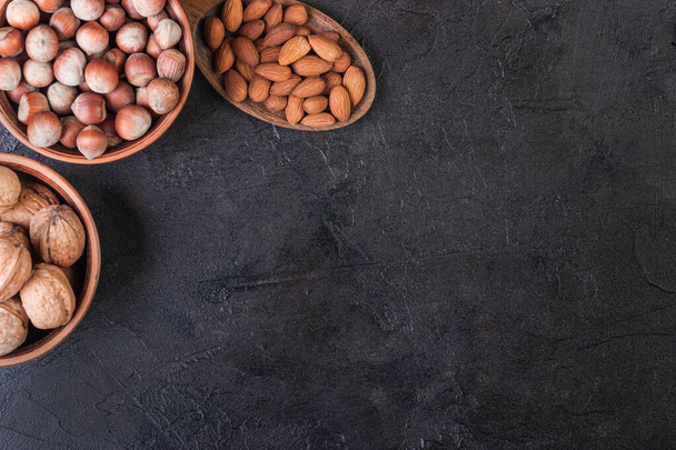 Walnut, hazelnuts and almonds in a spoon against a dark background - Foto, imagen