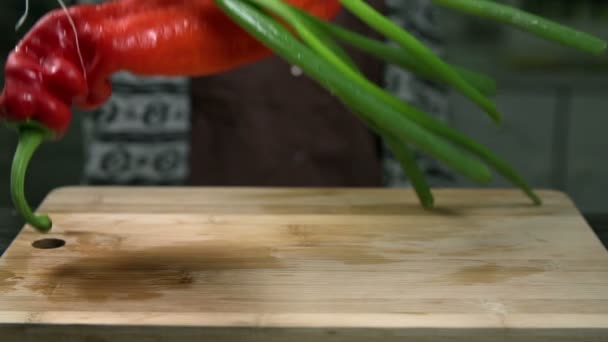 Large hot pepper and onions fall onto the wooden desk - Footage, Video