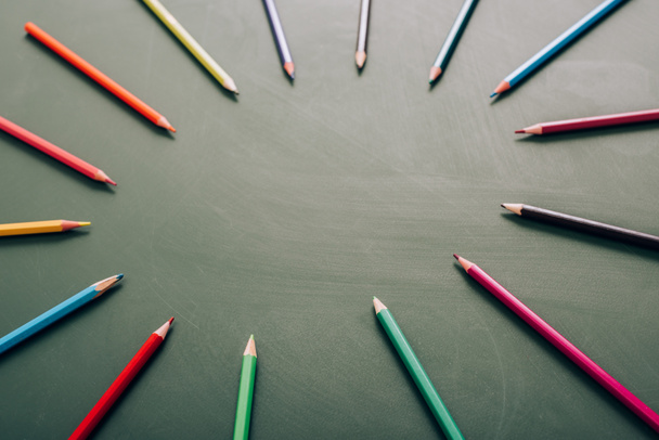 selective focus of circle frame of color pencils on green chalkboard, high angle view - 写真・画像
