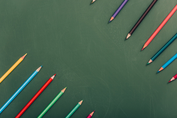 top view of multicolored pencils on green chalkboard - Фото, изображение