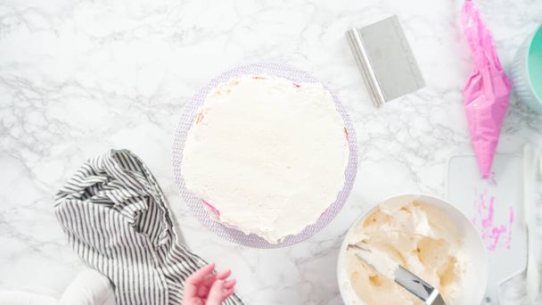 Pose plate. Pas à pas. Gâteau funfetti rond glaçant avec glaçage blanc à la crème au beurre italienne. - Photo, image