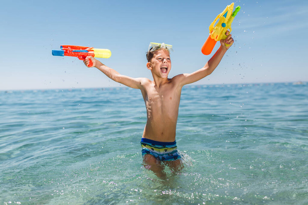 Adorabili ragazzi che giocano con le pistole ad acqua nella calda giornata estiva. - Foto, immagini