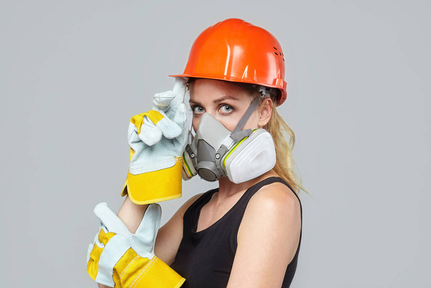 blonde woman in a respirator and a protective helmet. construction concept - Foto, Imagen