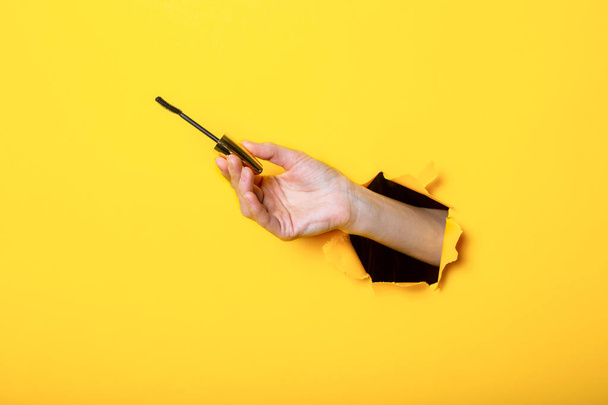 Кисть туши, женская рука держа кисть ресниц на желтом фоне - Фото, изображение