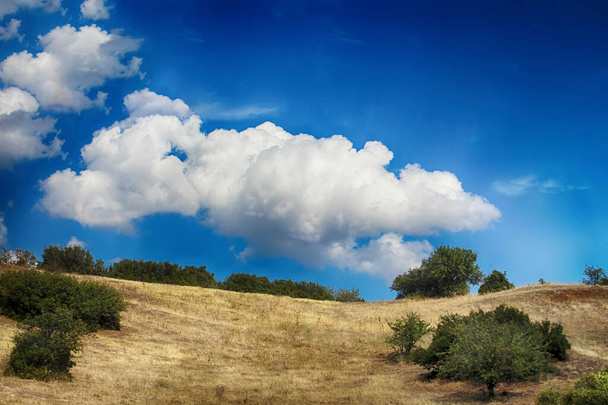 Чудова хмара між двома пагорбами, випалена трава. Літо
 - Фото, зображення