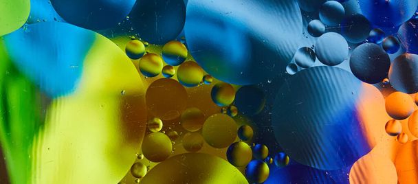 Abstract background with vibrant colors. Experiment with oil drops on water. Close up artful and colorful bubbles. Space pattern. - Фото, зображення