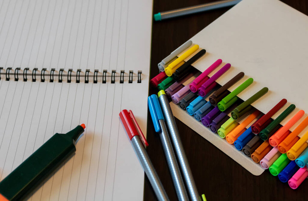 schoolbenodigdheden met kleurrijke pennen of aquarelpennen notitieboek en oranje markeerstift - Foto, afbeelding