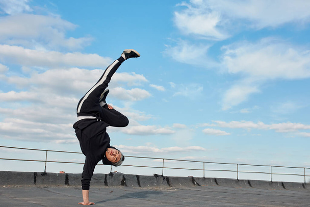 Korean urban style male dancer performing breakdance handstand on top roof - Fotoğraf, Görsel