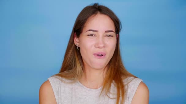 Selbstbewusste Frau im grauen T-Shirt nickt mit dem Kopf und sagt Nein auf blauem Hintergrund - Filmmaterial, Video