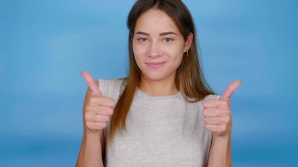 Onnellinen nainen harmaassa t-paidassa nostaa kätensä, näyttää peukalot ylös, tykkää ja hymyilee - Materiaali, video