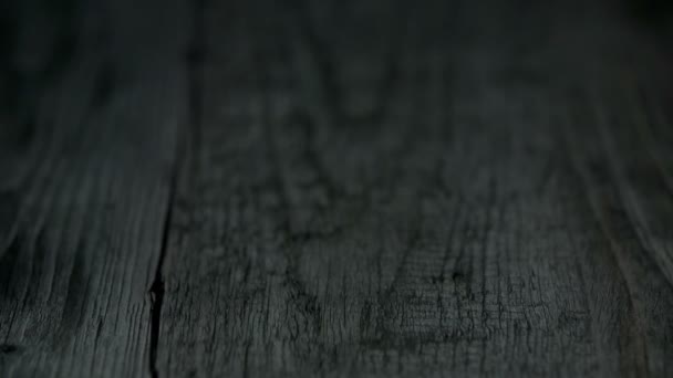 Laranja cortada cai sobre a superfície escura de madeira e se desintegra
 - Filmagem, Vídeo