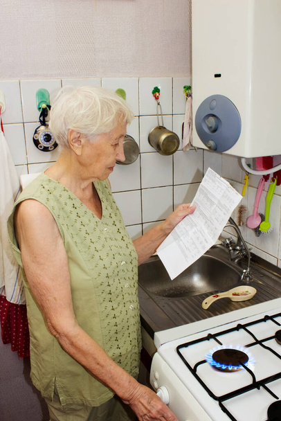 Die traurige Seniorin zu Hause und prüft die Gasrechnung. Sie steht beim Girokonto unter Stress. - Foto, Bild
