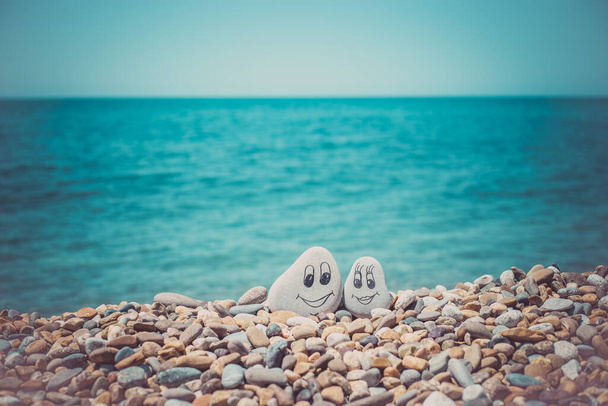 Kumda yüzleri çizilmiş çakıl taşları. Sevgi dolu bir çift. Seyahat kavramı. - Fotoğraf, Görsel
