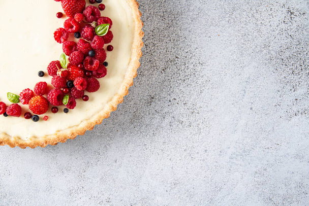 Gray textured background with a quarter of a pie with red berries in the corner. Berry Sand Cheesecake - Foto, imagen