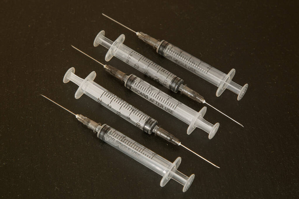 Seringas para injectáveis de 2, 5 ml num fundo escuro. Conceito de vacinação e apoio à saúde
 - Foto, Imagem